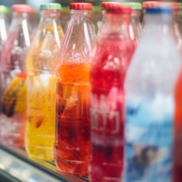 Brightly colored sodas in glass bottles in a refrigerated display